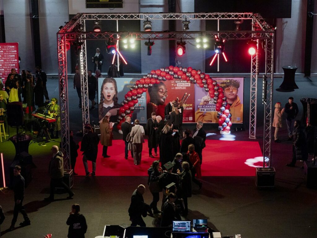 Gymnase transformé en salle de spectacle : tapis rouge, grill technique et arche de ballons pour le CNAM
