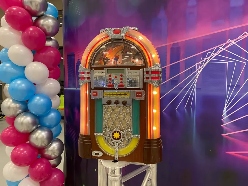 Juke-box lumineux et colonnes de ballons devant une toile néon