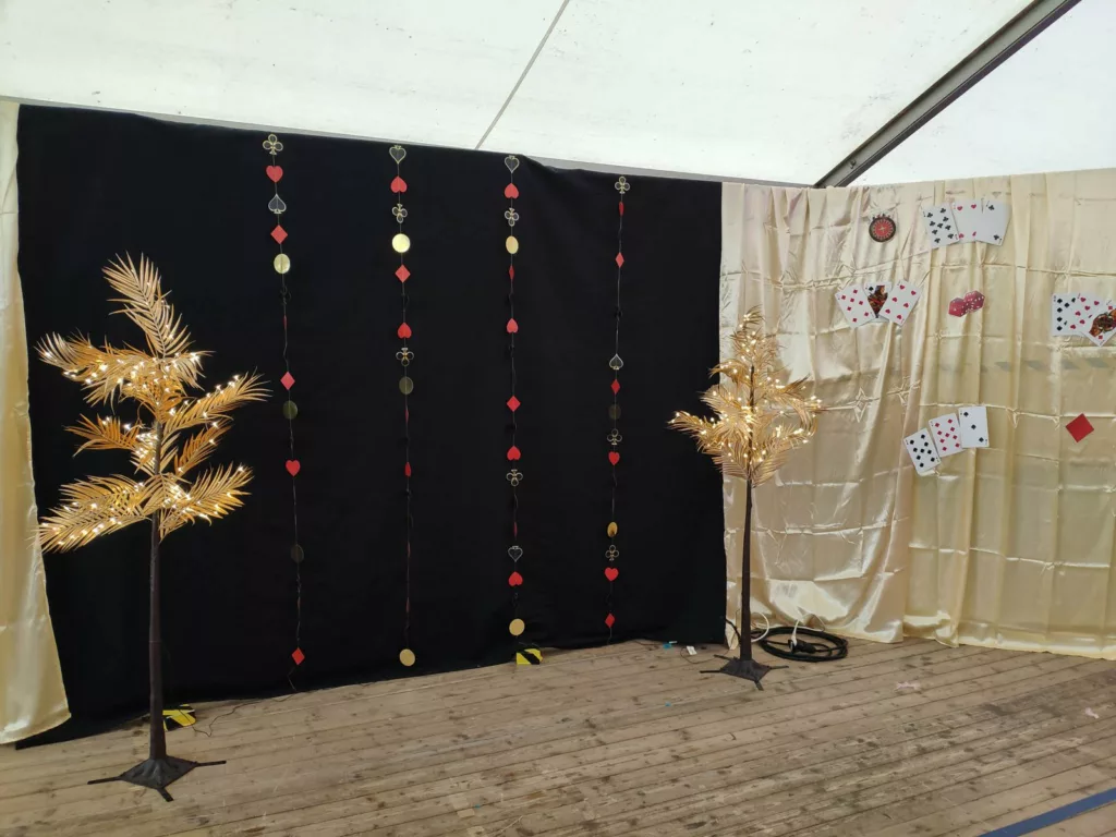 Photocall casino : rideau noir, guirlandes de cartes et arbres dorés